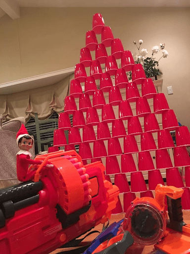 Elf on the Shelf Nerf Gun Pointed At A Solo Cup Tower