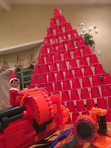 Elf on the Shelf Nerf Gun Pointed At A Solo Cup Tower