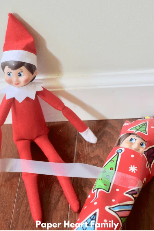 This mischievous Elf on the Shelf is wrapping her elf friend up. I wonder what he did?