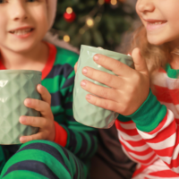 Kids drinking hot cocoa in front of the Christmas tree