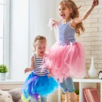 Sisters wearing tutus jumping on the bed together