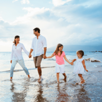 Family of four walking on the beach holding hands