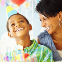 Black mom looking at her child as he's about to blow out the candles