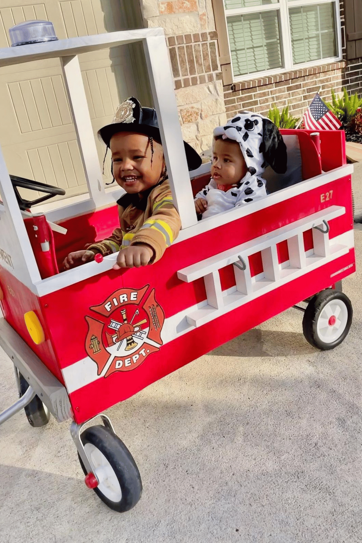 Baby as a dalmation and older brother as a fire fighter- both in a fire truck wagon