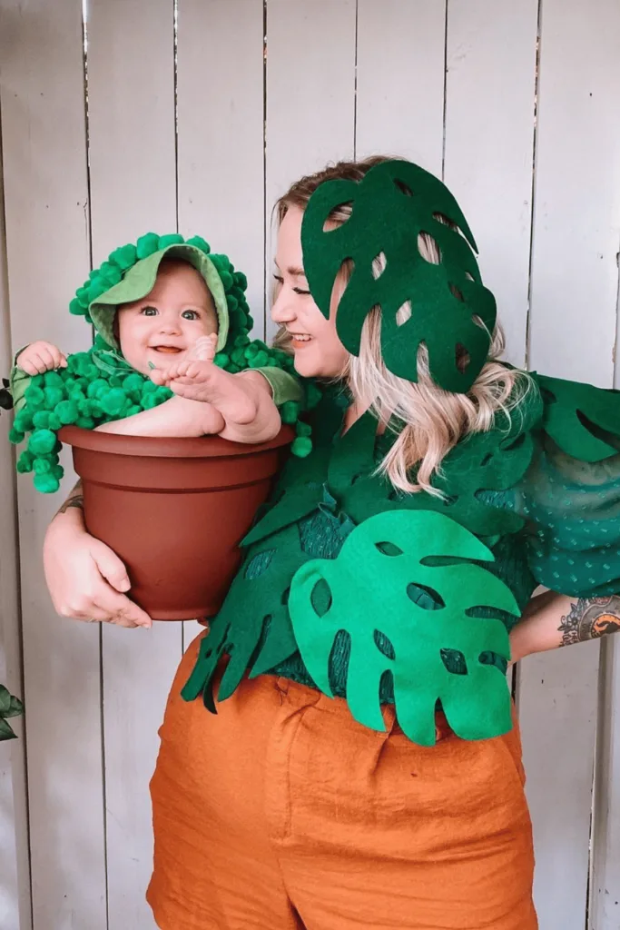 Mom dressed as a plant holding baby in a pot also dressed like a plant