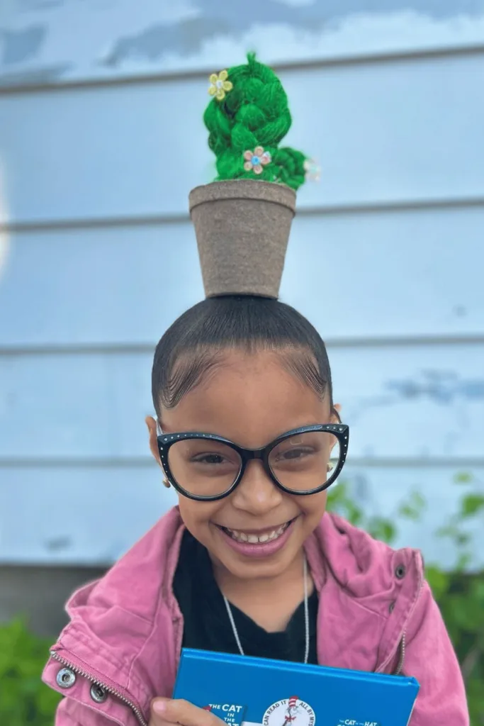 small pot with green braided hair and small flowers to look like a cactus