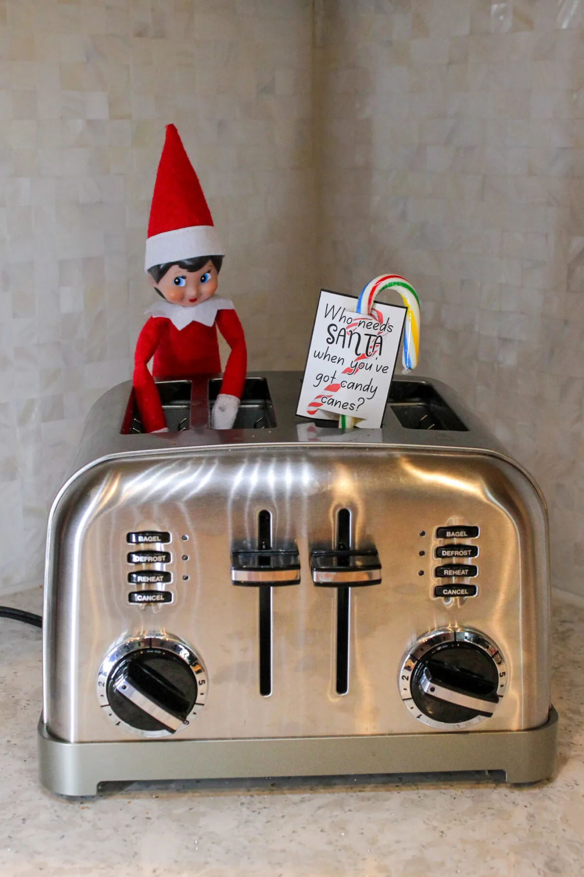 Elf on the Shelf sitting in the toaster with a candy cane