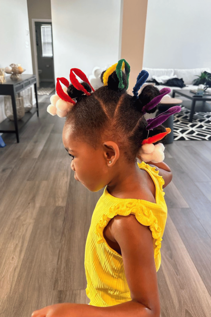 Pipe cleaner rainbow with clouds at the top and bottom of girl's hair