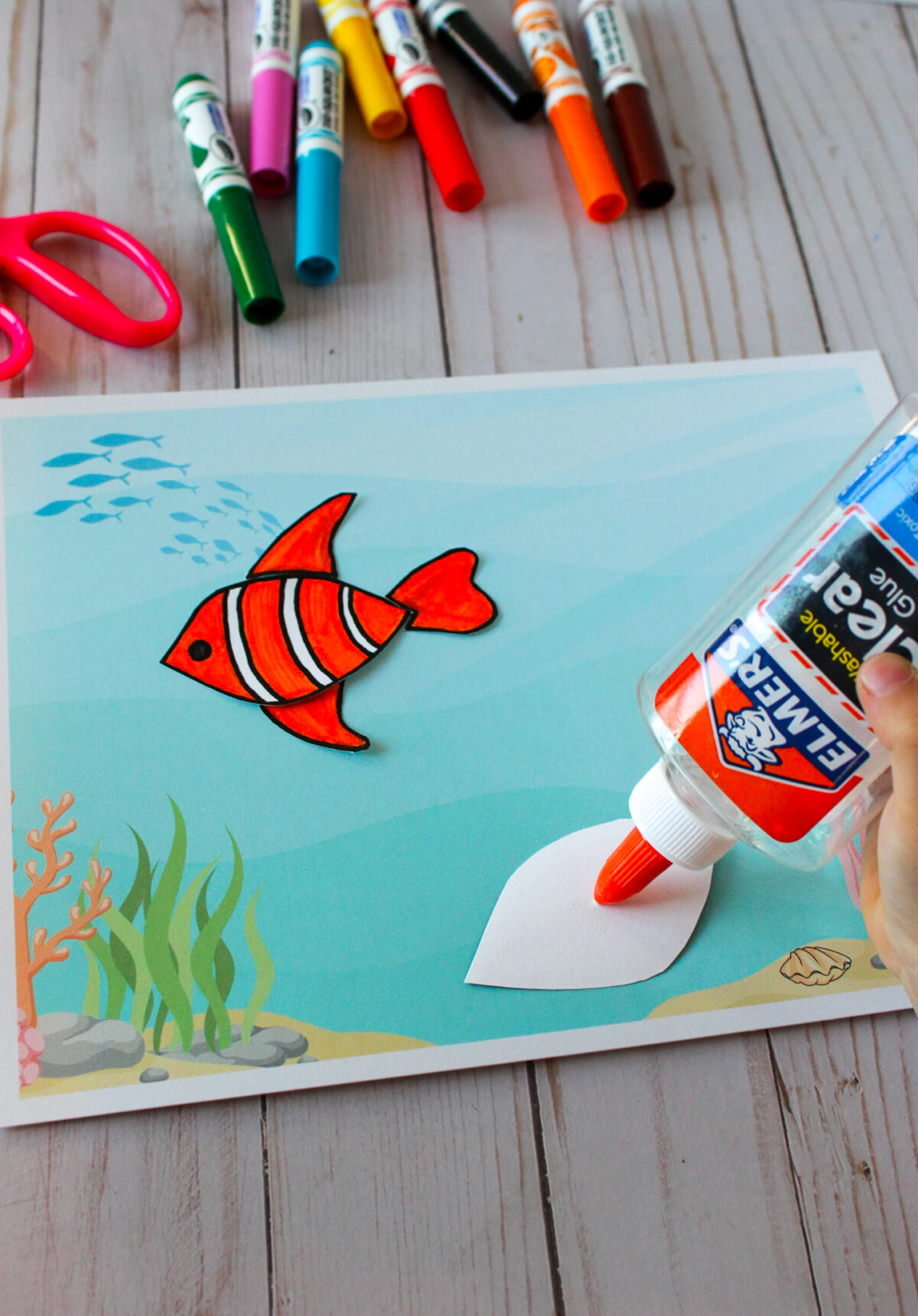 Girl putting glue on the back of a fish body