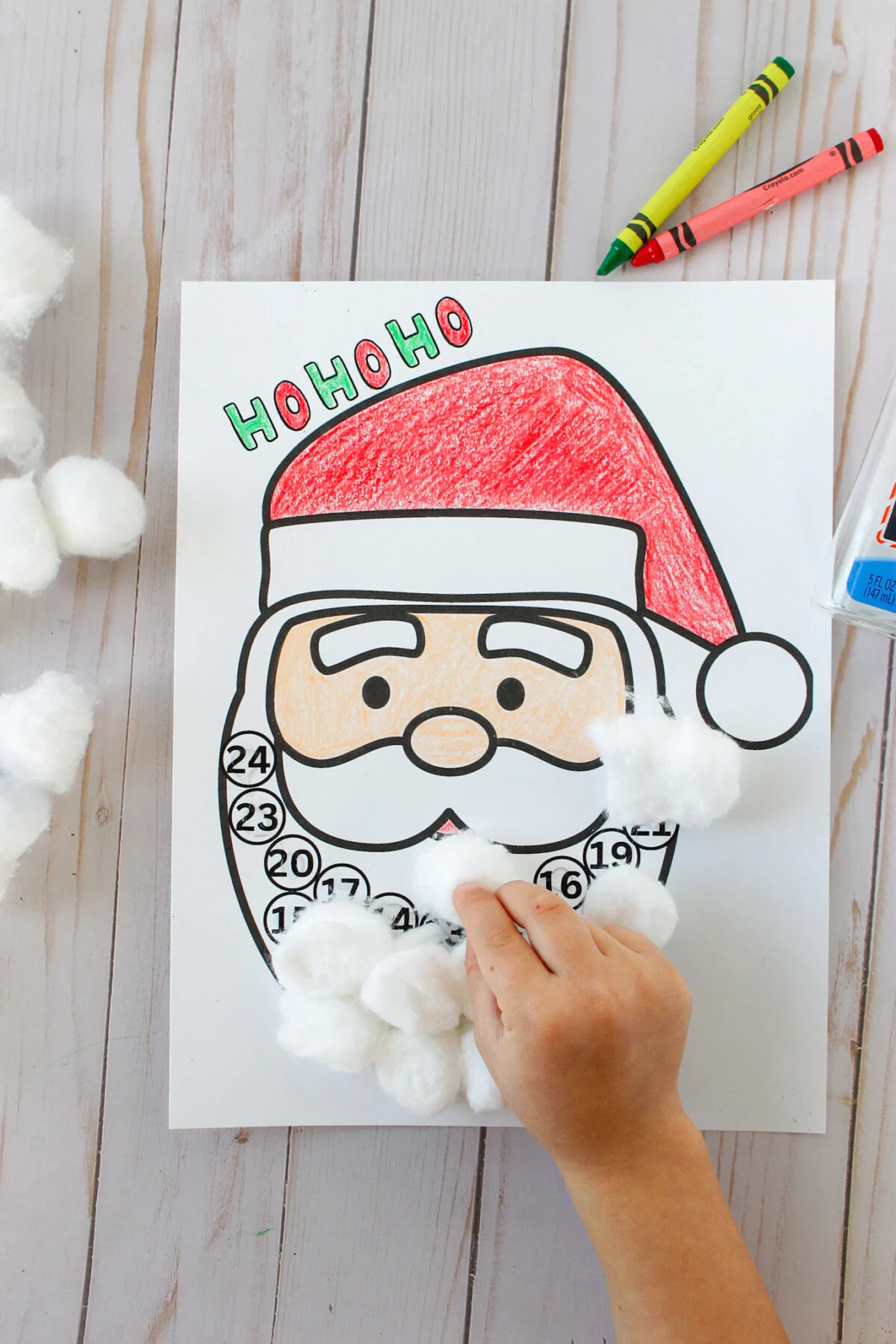 Child adding cotton balls to Santa's beard