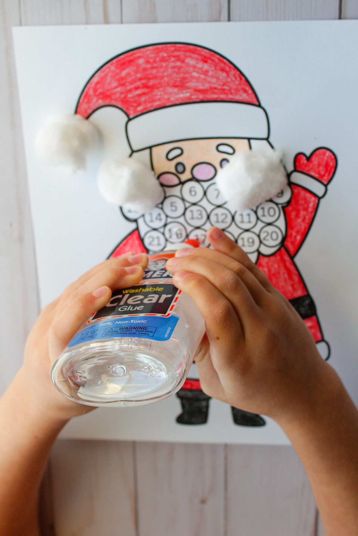 Child glueing cotton balls onto the Santa advent calendar